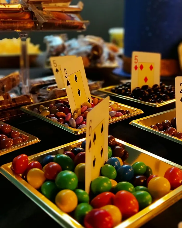 Mesa dulce con bandejas de chuches y naipes como carteles