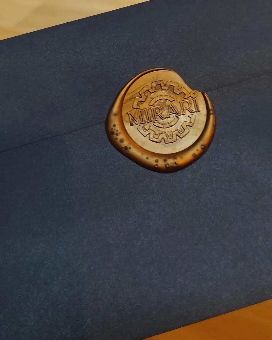 Sobre azul cerrado con un sello de lacre dorado con el logo de Mirari